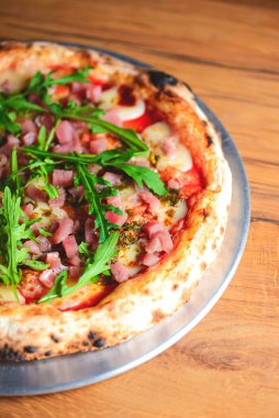 Kaba ahşap arka planda deniz ürünleri ve roka kaplı pizza. İtalyan mutfağı, İtalyan yemeği, geleneksel pizza tarifi..