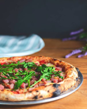 Kaba ahşap arka planda deniz ürünleri ve roka kaplı pizza. İtalyan mutfağı, İtalyan yemeği, geleneksel pizza tarifi..