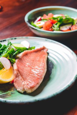 Balık tabağı - sebze salatalı kızarmış balık filetosu. Taze salatalık, turp ve ahşap masanın üzerinde kızarmış balıkla birlikte ıspanak. Sağlıklı beslenme, Ukrayna mutfağı kavramı.