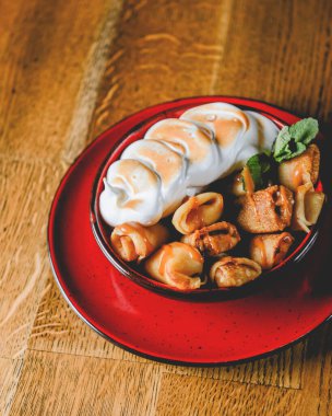 Fransız usulü krepleri yakın plan ahşap masa arkasında servis edilen bir tabakta sunulan kremalı sufle. Lezzetli tatlı, tatlı dolgulu krep..