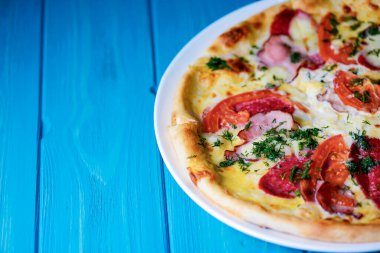 Eski mavi ahşap yüzey zemininde, fotokopi alanı ve kenar manzaralı pizza pişirdim. Fast food, abur cubur konsepti. İtalyan pizzası geleneksel tarifi.