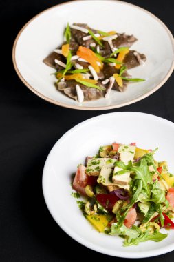 Taze mantarlı karabuğday köftesi ve peynirli sebze salatası, taze romatoes ve siyah arka planda beyaz tabakta servis edilen salatalıklar. Sağlıklı yeme kavramı.