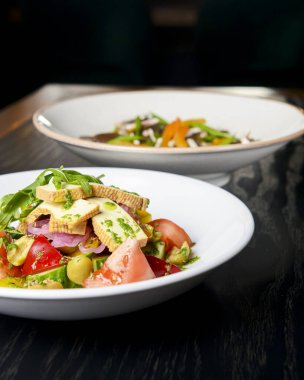 Taze mantarlı karabuğday köftesi ve peynirli sebze salatası, taze romatoes ve siyah arka planda beyaz tabakta servis edilen salatalıklar. Sağlıklı yeme kavramı.