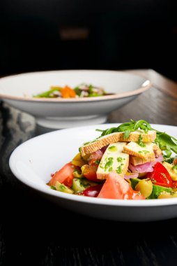 Taze mantarlı karabuğday köftesi ve peynirli sebze salatası, taze romatoes ve siyah arka planda beyaz tabakta servis edilen salatalıklar. Sağlıklı yeme kavramı.