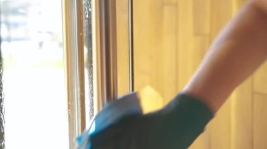 Tıbbi maske takan garson ve koruyucu eldivenler yüzeyleri dezenfekte ediyor. Önlüklü bir garsonu kapatın. Kapıları ve kapı kollarını çamaşır deterjanıyla temizleyin..