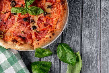 Salamlı ve siyah zeytinli taze İtalyan pizzası. Geleneksel İtalyan pizza tarifi, İtalyan mutfağı. Pizzaya yaklaş. Fast food, abur cubur konsepti. Kırsal ahşap zemin, düz zemin.