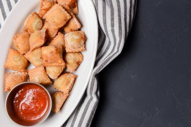 Etle doldurulmuş kızarmış hamur köftesi ve beyaz tabakta domates sosuyla servis edilmiş. Pelmeni tavada kızartılmış, Ukrayna mutfağı ve Rus mutfağı kavramı. Siyah arkaplanda.