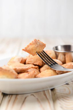 Etle doldurulmuş kızarmış hamur köftesi ve beyaz tabakta domates sosuyla servis edilmiş. Pelmeni tavada kızartılmış, Ukrayna mutfağı ve Rus mutfağı kavramı. Kırsal ahşap arka planda.