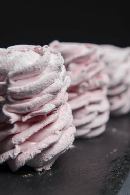 Marshmallow - karanlık bir arka planda zephyr. Siyah yerine çilek tadı olan pembe kabarık şekerleme. Kapat ve Zephyr 'e odaklan..