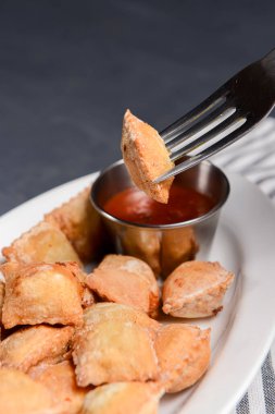 Etle doldurulmuş kızarmış hamur köftesi ve beyaz tabakta domates sosuyla servis edilmiş. Pelmeni tavada kızartılmış, Ukrayna mutfağı ve Rus mutfağı kavramı. Siyah arkaplanda.