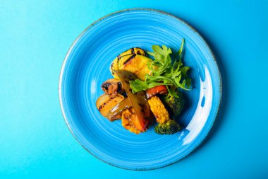 Mavi arka planda servis edilen lezzetli ızgara sebzeler. BBQ Grill konsepti, biftek ve patates için garnitür..