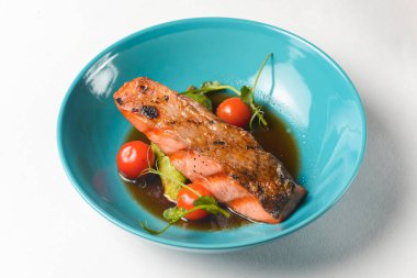 Beyaz arka planda mavi bir kasede servis edilen kiraz domatesli balık bifteği ve soya sosu. Lezzetli yemek fikri, sağlıklı yemek..