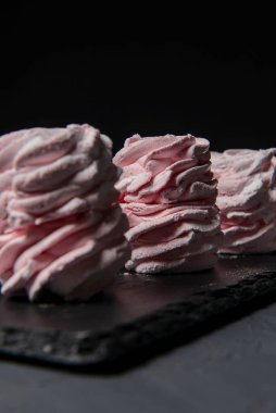 Marshmallow - karanlık bir arka planda zephyr. Siyah yerine çilek tadı olan pembe kabarık şekerleme. Kapat ve Zephyr 'e odaklan..