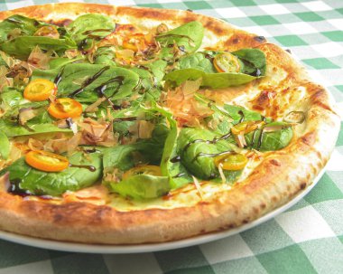 Tahta masada yeşil ekose masa örtüsüyle servis edilen ıspanaklı ve ton balıklı lezzetli pizza. İtalyan mutfağı, geleneksel pizza tarifi..