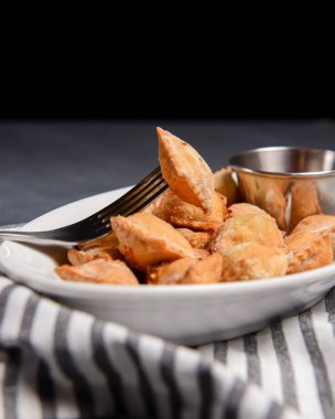 Etle doldurulmuş kızarmış hamur köftesi ve beyaz tabakta domates sosuyla servis edilmiş. Pelmeni ya da ravioli tavada kızartılmış, Ukrayna mutfağı ve Rus mutfağı kavramı. Siyah arkaplanda.