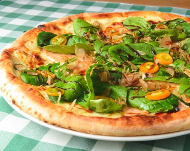 Tahta masada yeşil ekose masa örtüsüyle servis edilen ıspanaklı ve ton balıklı lezzetli pizza. İtalyan mutfağı, geleneksel pizza tarifi..