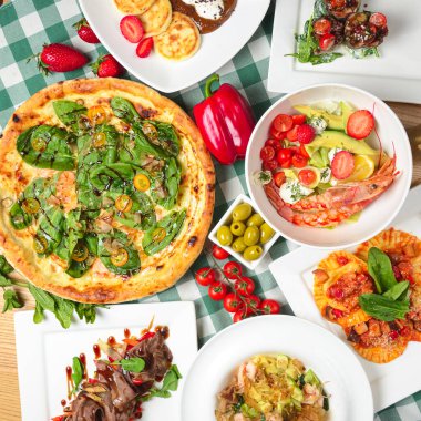 Ton balığı ve ıspanaklı pizza, karidesli salata ve avokado, raviolli, deniz makarnası, çikolatalı kremalı vanilyalı peynirli kek ve taze çilek. İtalyan mutfağı konsepti, İtalyan yemekleri..