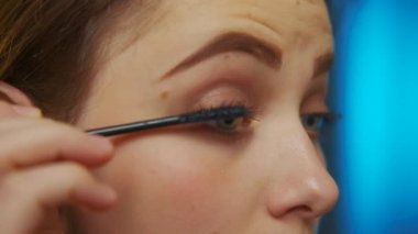 Genç ve çekici bir kadın makyaj yapıyor. Güzellik endüstrisi konsepti, beyaz bir kadının hazırlanması. Sabahları hazırlanıyor, gülümsüyor güzel kız makyaj yapıyor, yüzüne makyaj yapıyor..