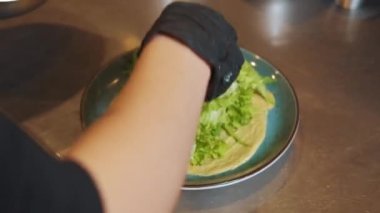 Sebzeli taze salata ve tabakta biftek, salata yapma süreci. Mutfakta çalışan bir aşçı. Restoran kompleksi. Malzemeleri tabağa koy: domates, soğan, roka..