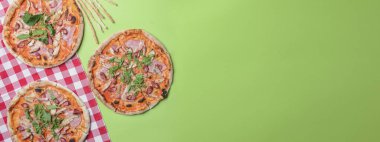 Yeşil masada servis edilen lezzetli İtalyan pizzaları. Parlak yeşil ekranlı üç pizza, web sitesi tasarım afişini kopyala. İtalyan konsepti, düz yatak.