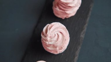 Siyaha servis edilen üç pembe zephyr kurabiyesinde panorama manzarasını kapat. Şekerleme ya da zephyr - tatlı çilek tadı. Siyah üzerine tatlı yavaş çekim görüntüsü.