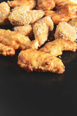 Lezzetli kızarmış tavuk kanatları ve bacakları siyaha karşı. Bira atıştırmalıkları, parti için akşam yemeği. Fast food, abur cubur kavramı.