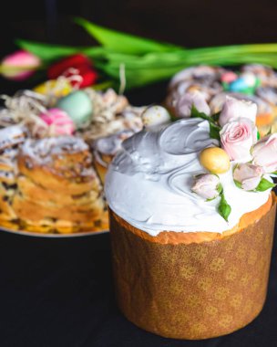 Üstünde güller ve paskalya yumurtaları olan paskalya pastası. İçinde beyaz krema ve kuru üzüm var. Bahar, Paskalya kutlaması konsepti. Tatil için geleneksel yemek. Kara sırtlı.