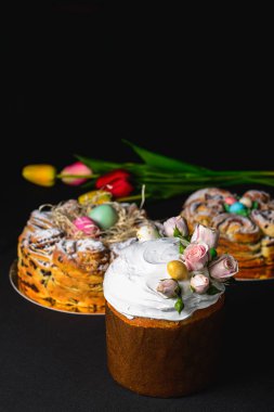 Üstünde güller ve paskalya yumurtaları olan paskalya pastası. İçinde beyaz krema ve kuru üzüm var. Bahar, Paskalya kutlaması konsepti. Tatil için geleneksel yemek. Kara sırtlı.