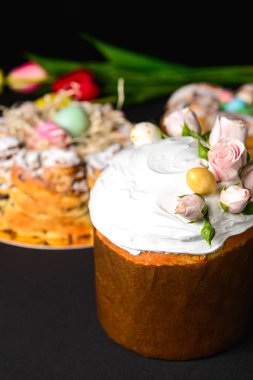 Üstünde güller ve paskalya yumurtaları olan paskalya pastası. İçinde beyaz krema ve kuru üzüm var. Bahar, Paskalya kutlaması konsepti. Tatil için geleneksel yemek. Kara sırtlı.