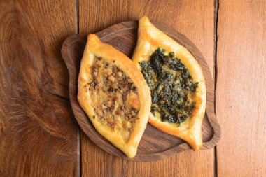 Etli, mantarlı ve yeşillikli Khachapuri. Sığır filetosundan, mantardan, krema sosundan, şifalı otlardan yapılmış. Khachapuri yuvarlak ışıklı ahşap bir tahtada servis edilir. Geleneksel Gürcistan mutfağı kavramı.