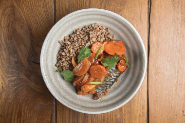 Kırsal ahşap arka planda seramik tabakta balıklı karabuğday lapası. Gürcistan mutfağı, sağlıklı yemek fikri.