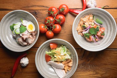 Sebze ve etten yapılmış üç çeşit Gürcistan mutfağı salatası sade ahşap arka planda servis edilen ve sarımsaklı, kırmızı hor biberli domatesli ibn kaseleri. Gürcistan mutfağı kavramı.