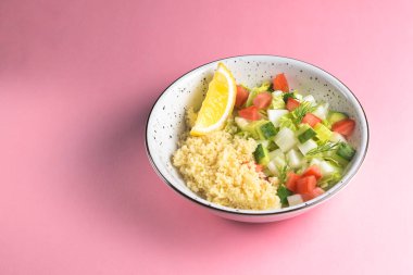 Pastel pembe arka planda sebzeli bulgur. Lezzetli, sağlıklı bir yemek kasesi. Yaklaş..