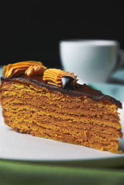 Beyaz tabakta kremalı bir parça çikolatalı pasta. Bir fincan sade kahveyle servis edilir. Tatlı zamanı..