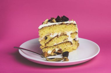 Fıstıklı kek, beyaz tabakta fındıklı kek. Pembe arka planda taze pişmiş bir parça kek. Tatlı zamanı..