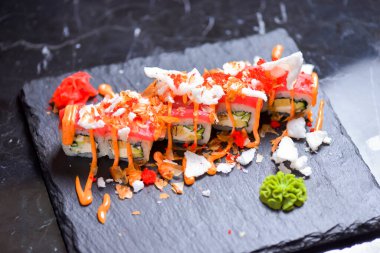 Somon, ton balığı, avokado, krem peynir ve tutkulu meyve sosuyla Philadelphia usulü suşi. Suşi menüsü. Japon yemeği. Yakın çekim, seçici odaklanma, bulanık bir arka plan. Geleneksel tarif.