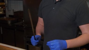 Şişe kebap yapıyor, şişe çiğ et koyuyor. İçeride, aşçı mutfakta çalışıyor..