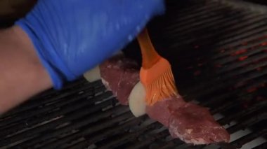 Şef mangal kömürünün üstüne etli şiş koyuyor. Şişte et. Restoran kompleksi.