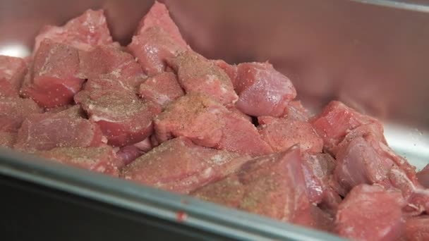 Primer plano de una carne cruda cortada en trozos para shashlik o shish kebab espolvoreado de sal marina y otras especias en bandeja de metal. — Vídeos de Stock