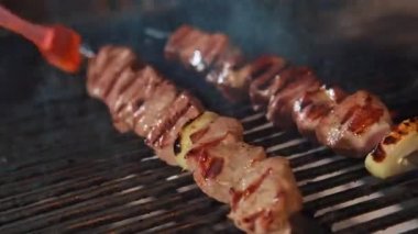 Şef mangal kömürünün üstüne etli şiş koyuyor. Şişte et. Restoran kompleksi.