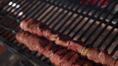Şef mangal kömürünün üstüne etli şiş koyuyor. Şişte et. Restoran kompleksi.