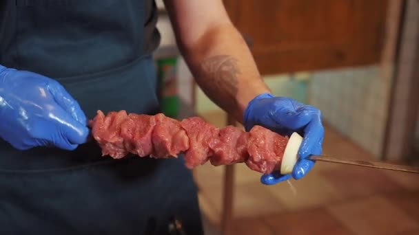 Шеф-повар делает шашлык на шампуре, кладет сырое мясо на шампур. Внутри, шеф-повар работает на кухне, рабочий процесс. — стоковое видео