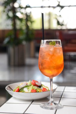Restoran masası, bir tabak salata ve bir bardak meyve kokteyli. Sağlıklı beslenme konsepti, restoranda tek başına yemek, sosyalleşme..