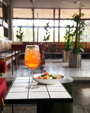 Restoran masası, bir tabak salata ve bir bardak meyve kokteyli. Sağlıklı beslenme konsepti, restoranda tek başına yemek, sosyalleşme..