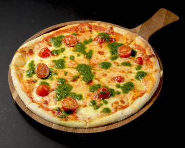 Kiraz domatesli ve fesleğen soslu pizza, siyah arka planda kırsal taze pizza. Geleneksel İtalyan mutfağı kavramı.
