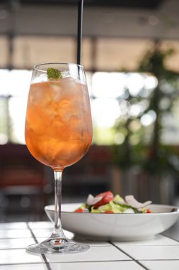 Restoran masası, bir tabak salata ve bir bardak meyve kokteyli. Sağlıklı beslenme konsepti, restoranda tek başına yemek, sosyalleşme..