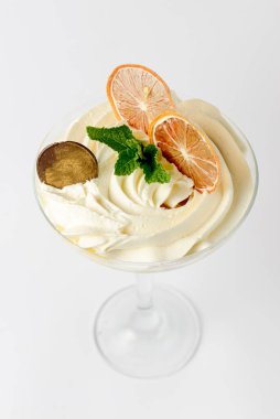 Büyük bardakta limonlu tiramisu bir parça çikolata ve beyaz arka planda kurutulmuş portakal dilimleri ile servis edilir. İtalyan mutfağı konsepti, geleneksel meyve tarifi.