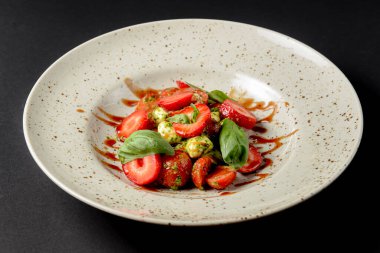 Çilekli Caprese salatası. Mozzarella, domates, fesleğen ve çilekli salata. Siyah arka planda. Sağlıklı beslenme konsepti. İtalyan mutfağı.