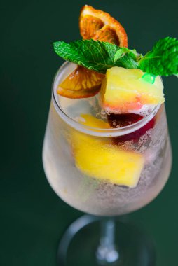 Mango ve tutkulu meyve kokteyli naneli. Yeşil arka planda uzun bir bardakta lezzetli bir meyve suyu. Alkolik içecek..