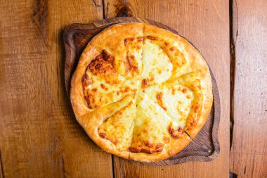 Khachapuri turtası ve peynir ahşap arka planda tahtadan servis ediliyor. Gürcistan mutfağı kavramı, geleneksel Khachapuri tarifi.